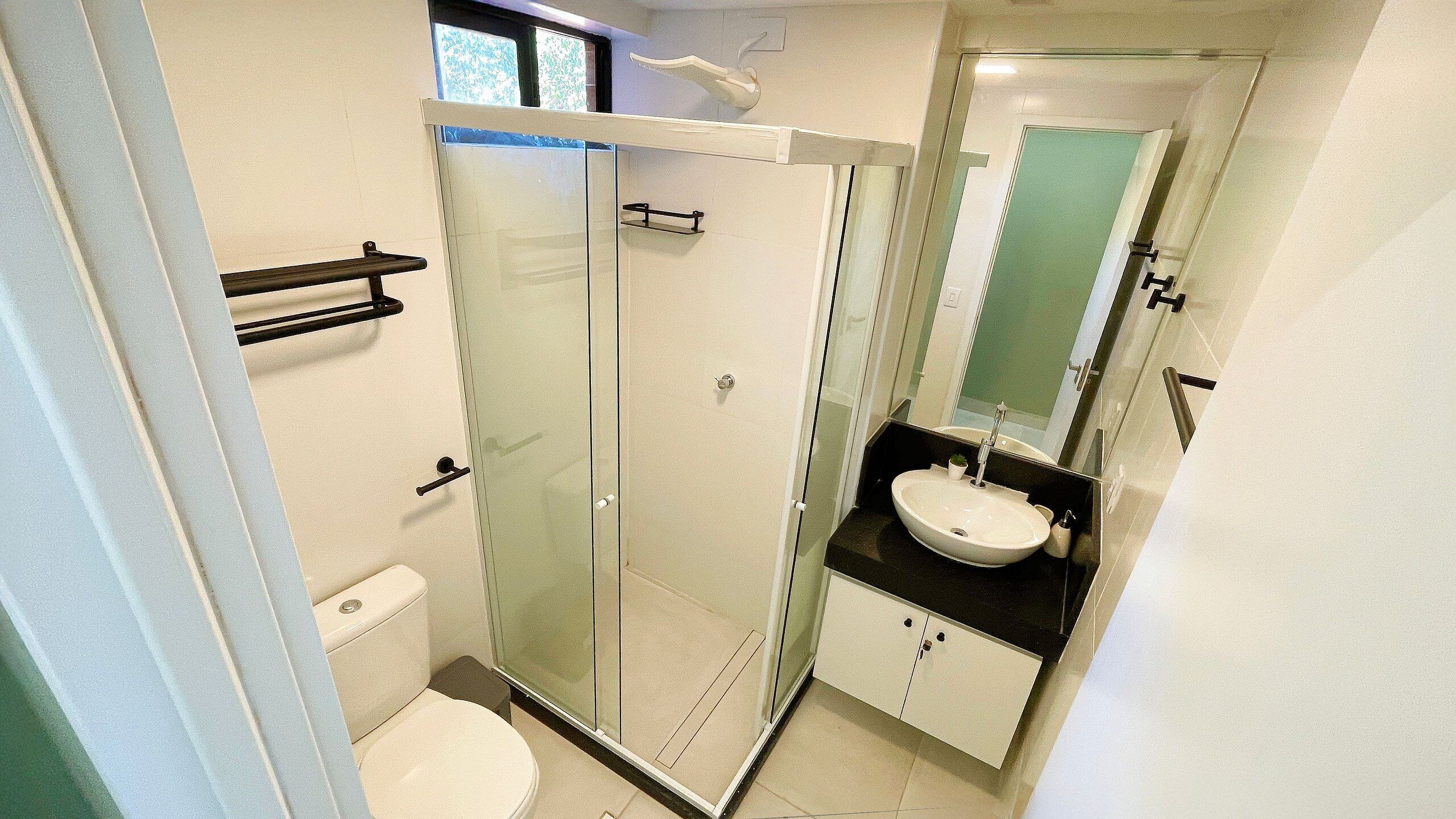A modern bathroom with a glass-enclosed shower, a white sink, and a toilet.