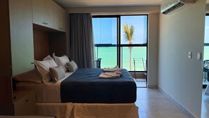 Un dormitori amb llit, almoines, vista al mar i un balcó amb una cadira.