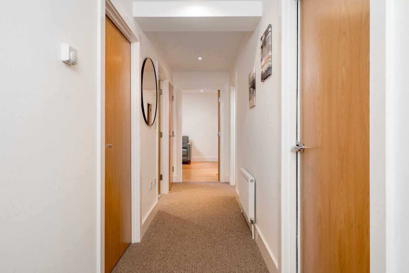 A hallway with wooden doors, a radiator, and a grey chair in the distance.