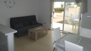 A living room with a sofa, coffee table, and a dining area with a table and chairs.
