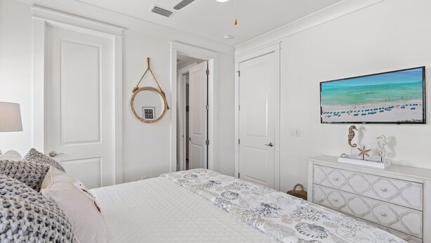 Una camera da letto con un letto, una ventola a soffitto, una televisione e un comò.