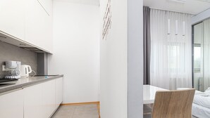 Una habitación de hotel moderna con kitchenette, comedor y cama.