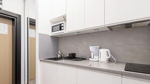 Una cocina moderna con microondas, cafetera y una placa de inducción negra.