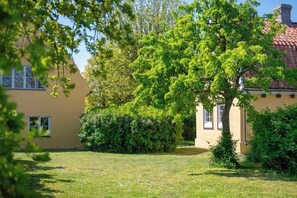 A building with a yellow facade, surrounded by lush greenery and trees.