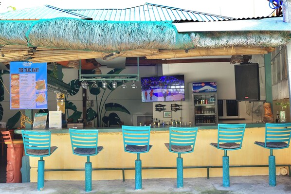 Zona de bar con sillas a rayas turquesa y una pizarra de menú.