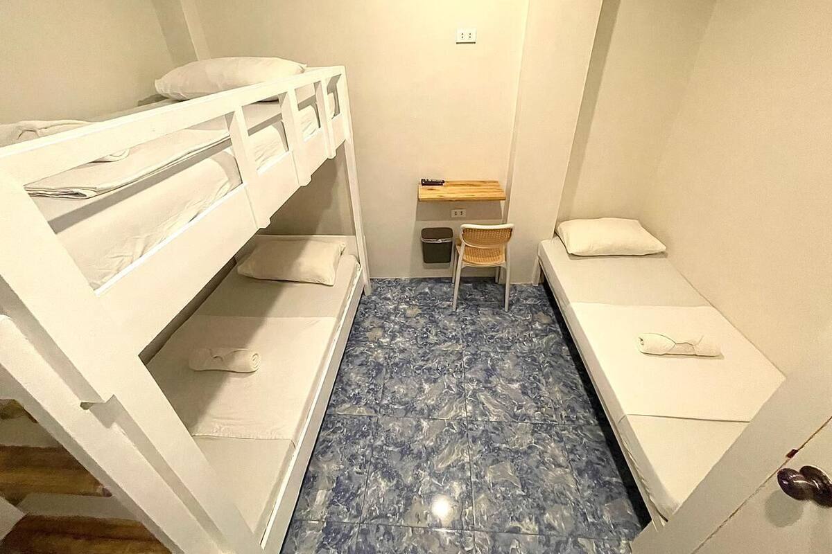 Ein kleiner, kompakter Raum mit Etagenbetten, einem Tisch und einem Stuhl.