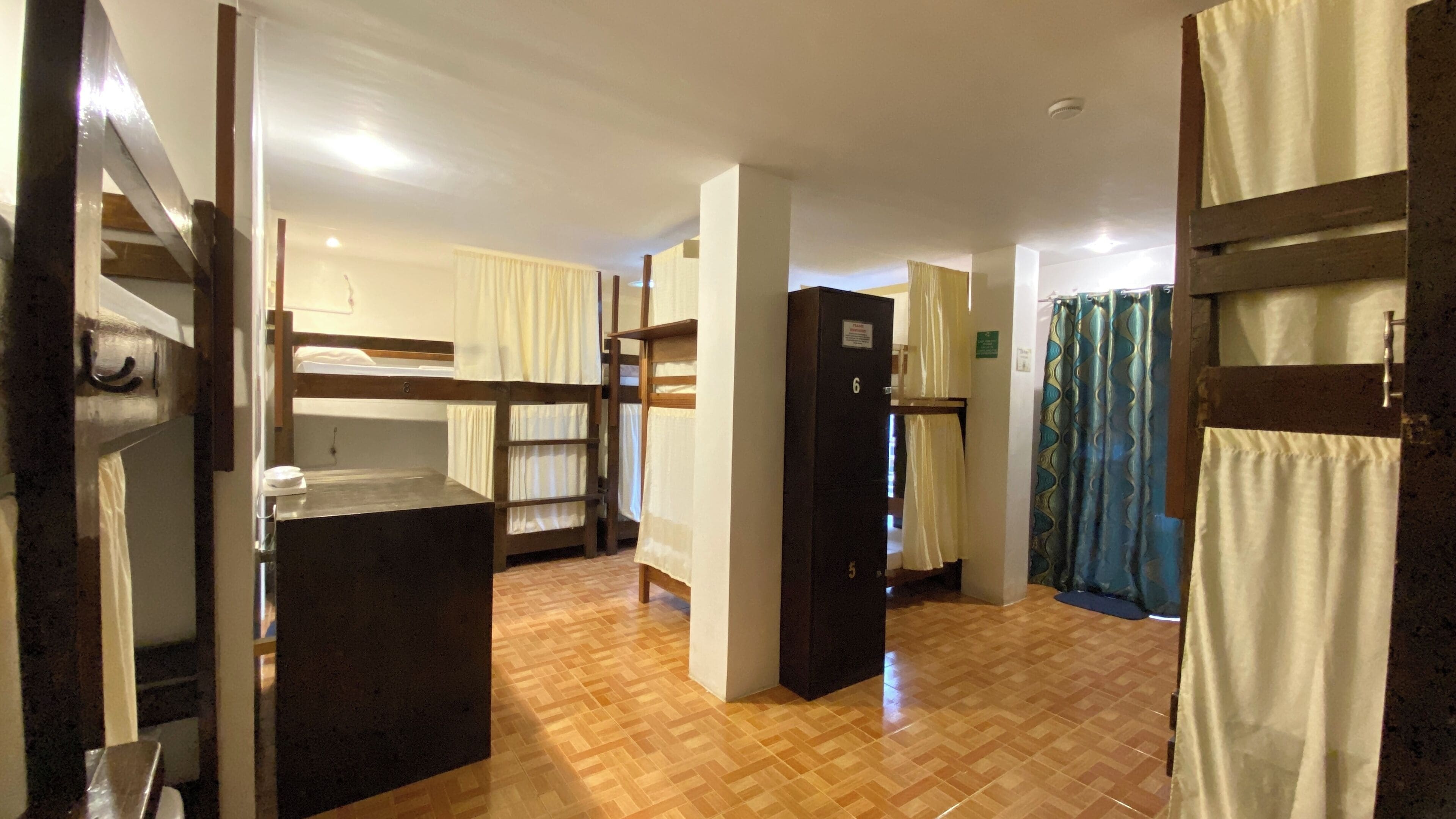 A dormitory room with bunk beds, a wardrobe, and a shower area.