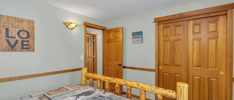 A bedroom with a bed, wooden doors, a wall with motivational quotes, and a patterned rug.