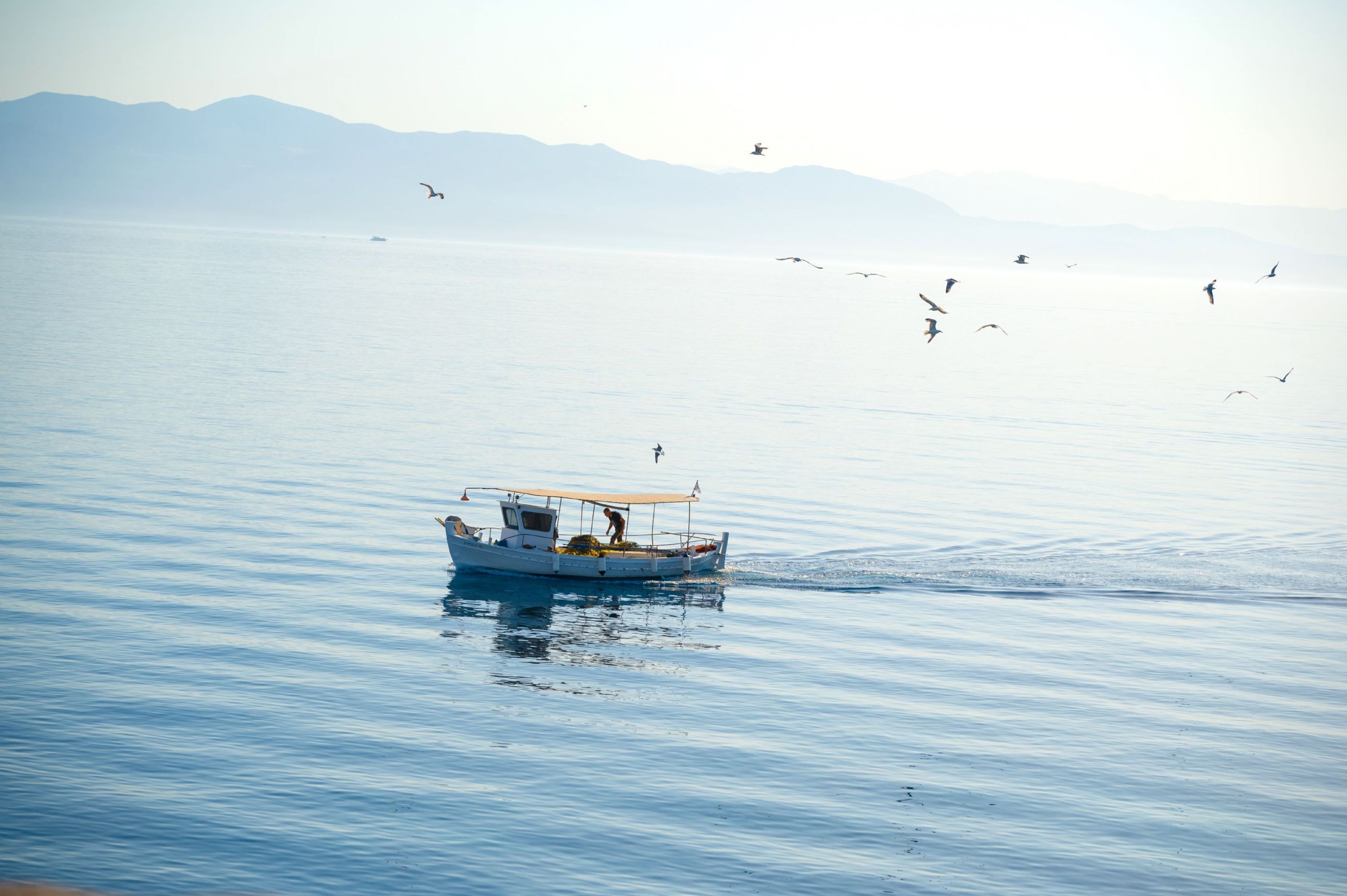 A small boat on calm water with mountains in the background.