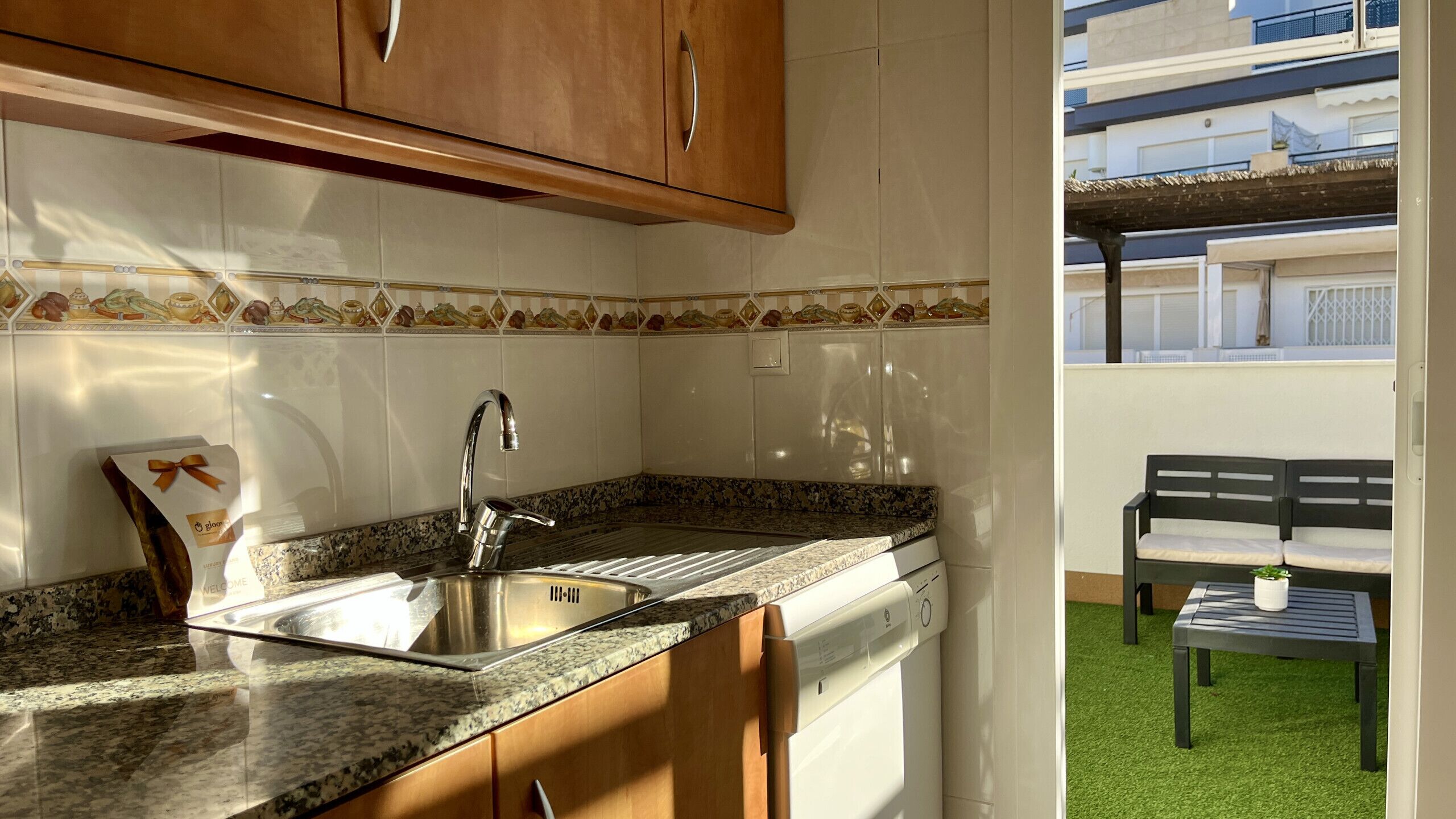 A kitchen with a granite countertop, stainless steel sink, and wooden cabinets.