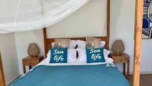 A bed with a canopy, two pillows with "Sea life" text, a blue bedspread, and two nightstands with lamps.