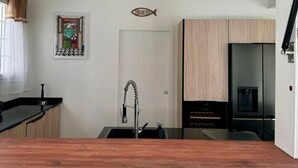 A modern kitchen with a wooden countertop, a stainless steel sink, and a white door.