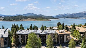 A hotel with a view of a lake and mountains, featuring a modern architectural style with multiple floors and a flat roof. - Stunning 2BR on Lake Dillon w/ Pool and Concert Access! (Dillon)