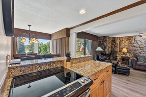 Una cocina moderna con encimeras de granito, estufa integrada y una pared de acento de piedra.