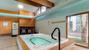 A spa room with a hot tub, wooden steps, a window with a view of the outside, and a sign on the wall. - Stunning 2BR on Lake Dillon w/ Pool and Concert Access! (Dillon)