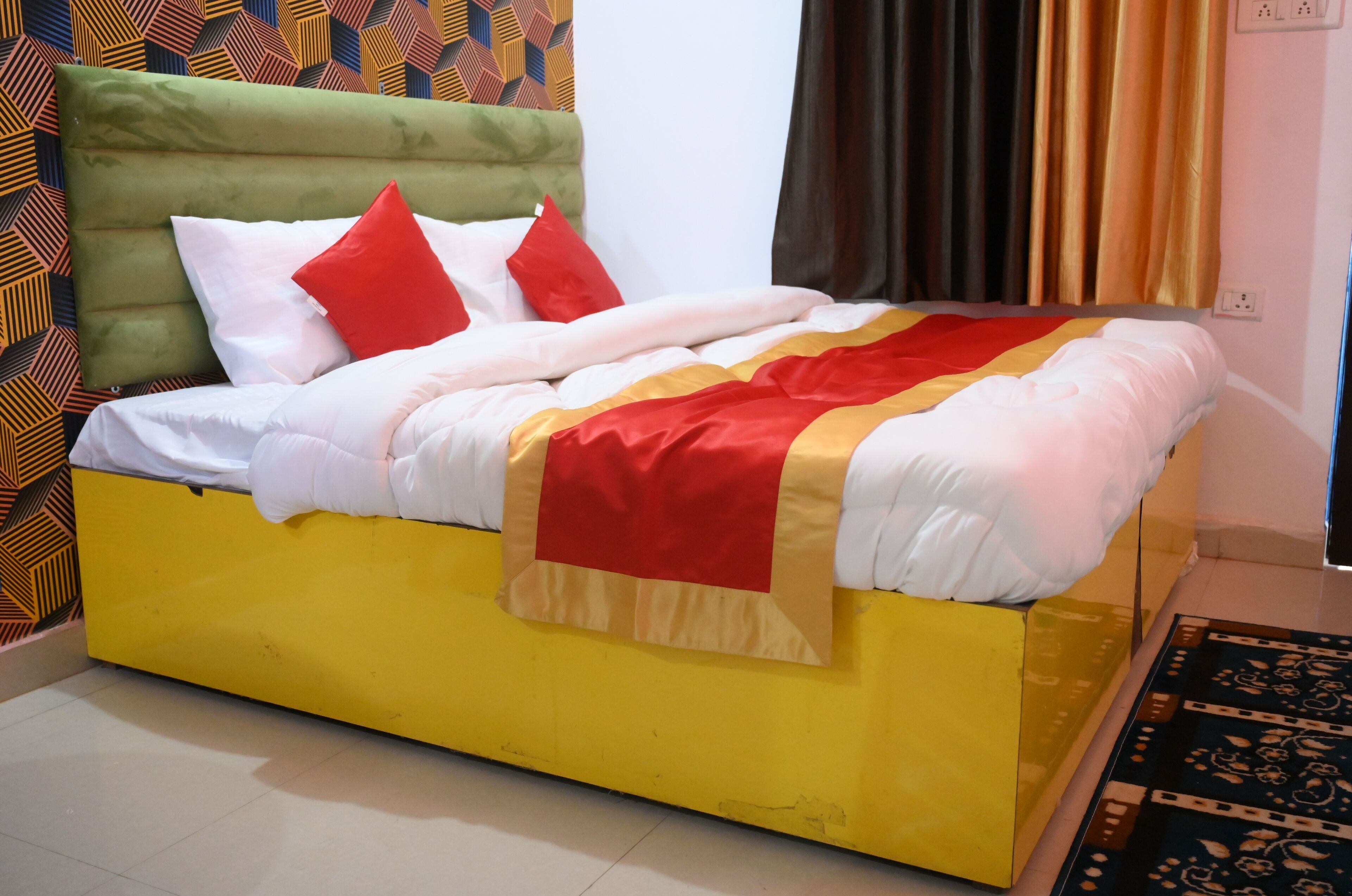 A bed with a green headboard, white and red bedding, and a yellow base.