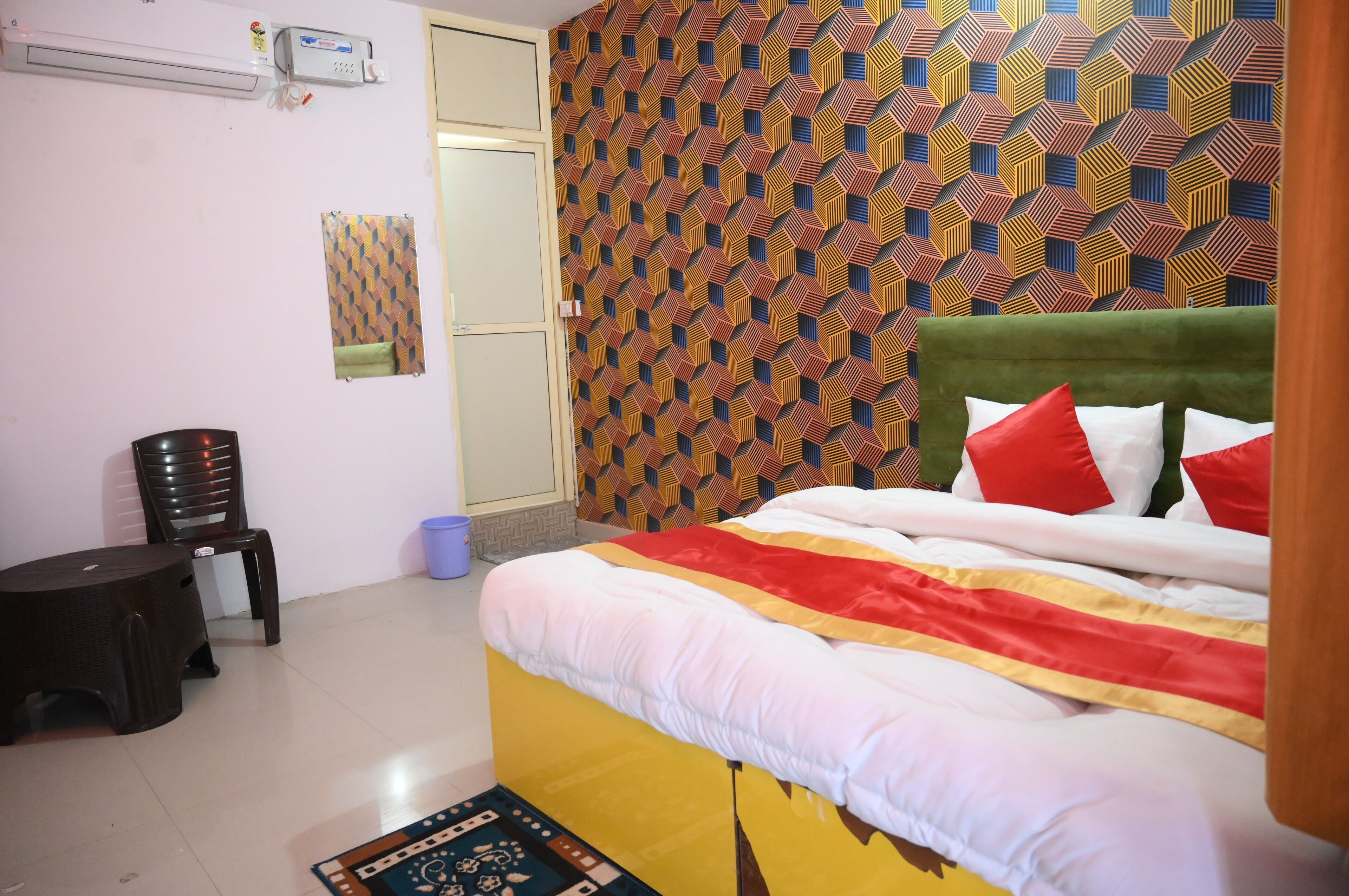 Ein Schlafzimmer mit einem gemusterten Wand, einem Bett mit roten und weißen Kissen und einem kleinen Tisch mit einem Stuhl.