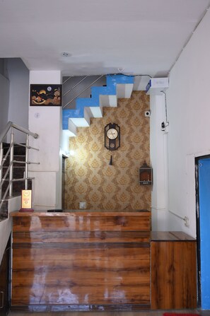 A staircase with a wooden finish, a clock, and patterned wallpaper.