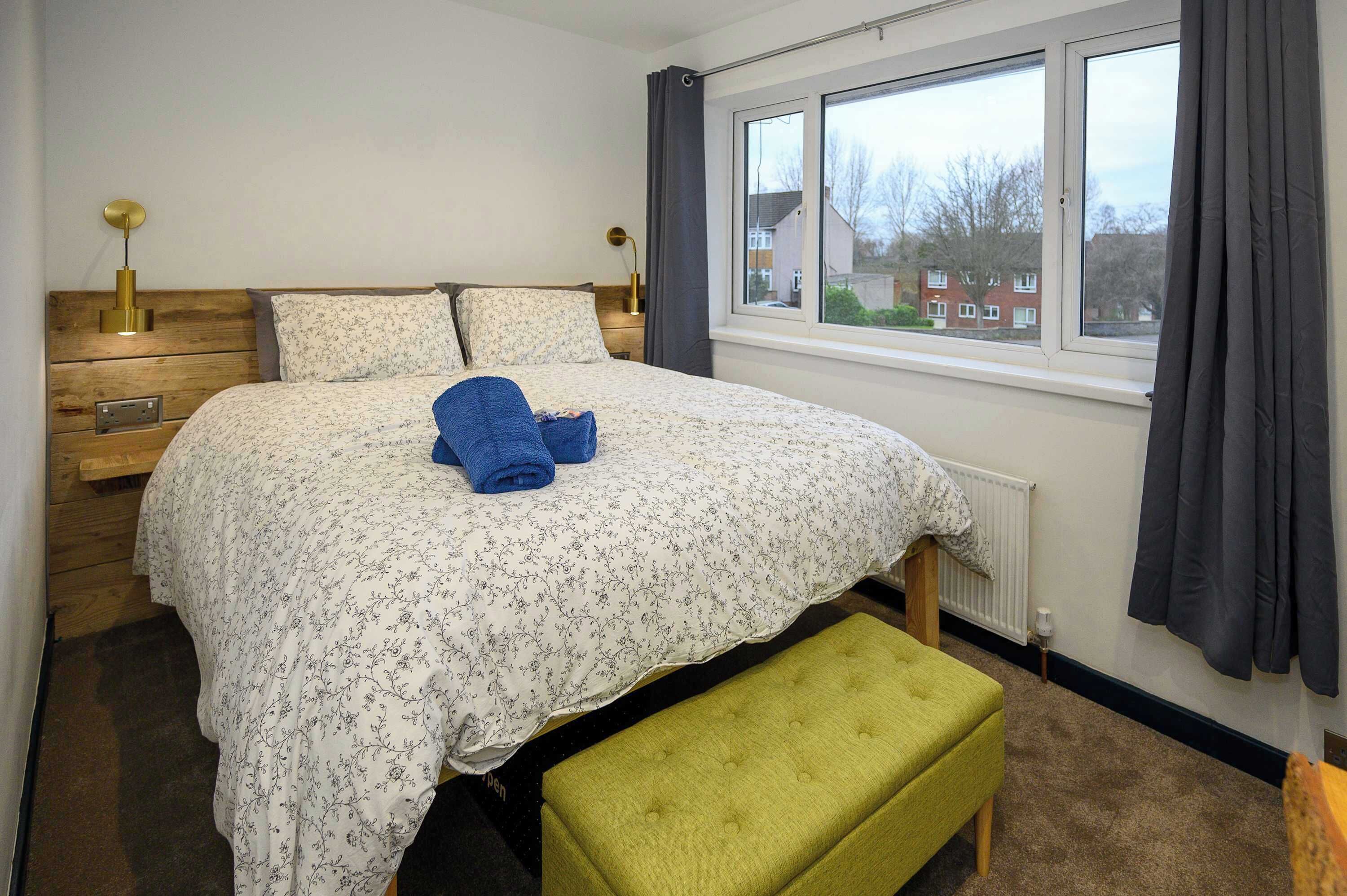 Une chambre à coucher avec un lit, un banc, une fenêtre et une vue sur l’extérieur.