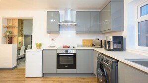 Een compacte keuken met grijze kastjes, een Bosch oven, een vaatwasser en een magnetron.