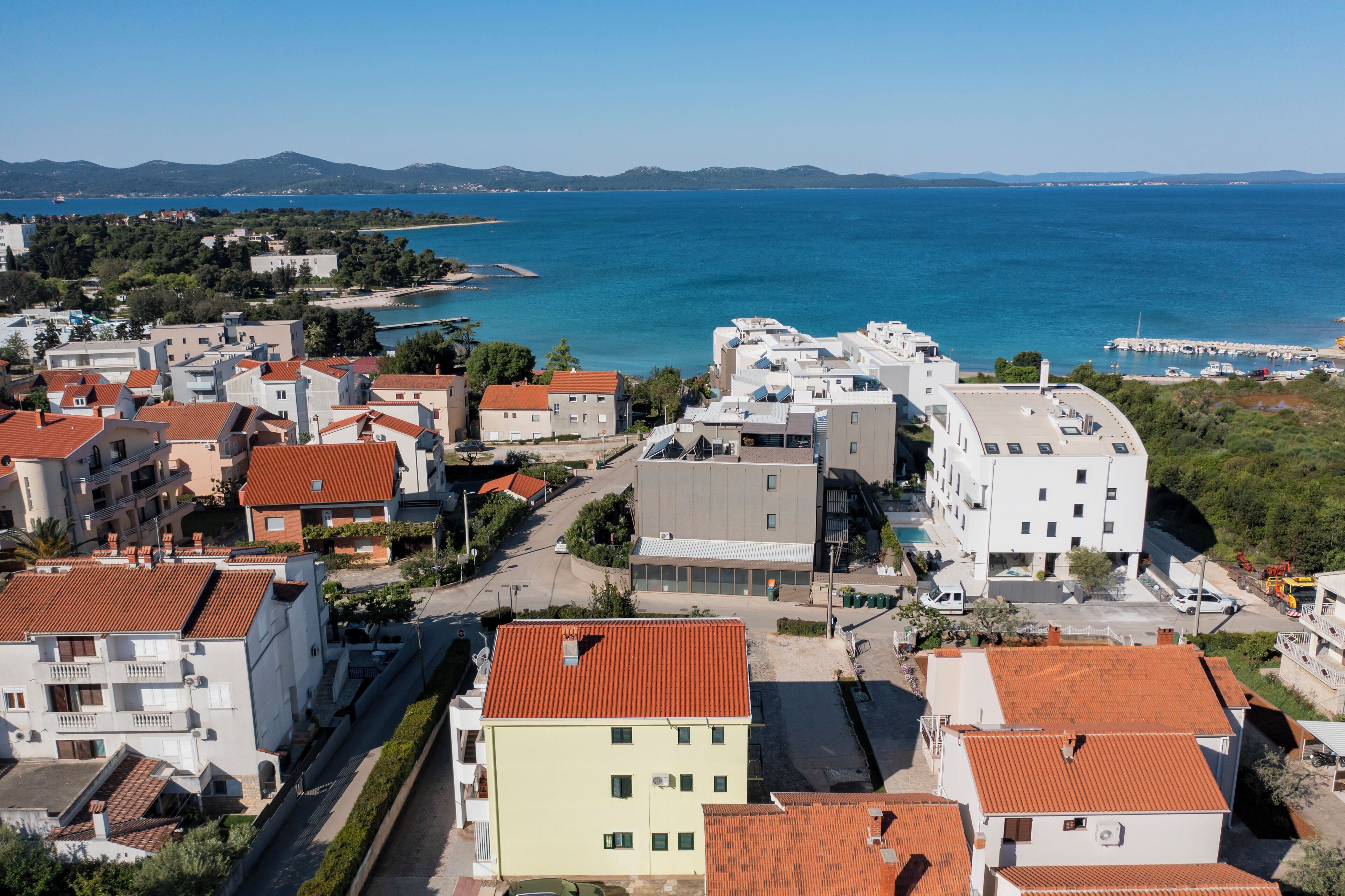 A coastal town with buildings, a road, and a view of the sea.