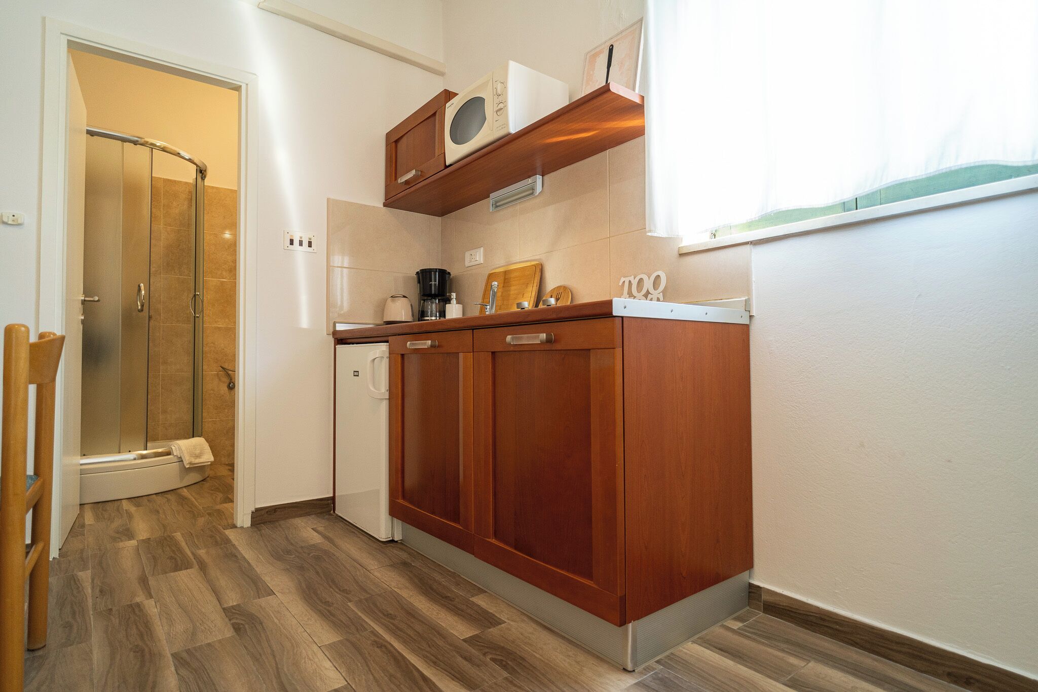 A compact kitchen with wooden cabinets, a microwave, and a coffee maker.
