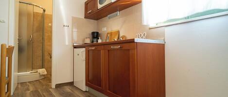 A compact kitchen with wooden cabinets, a microwave, and a coffee maker.
