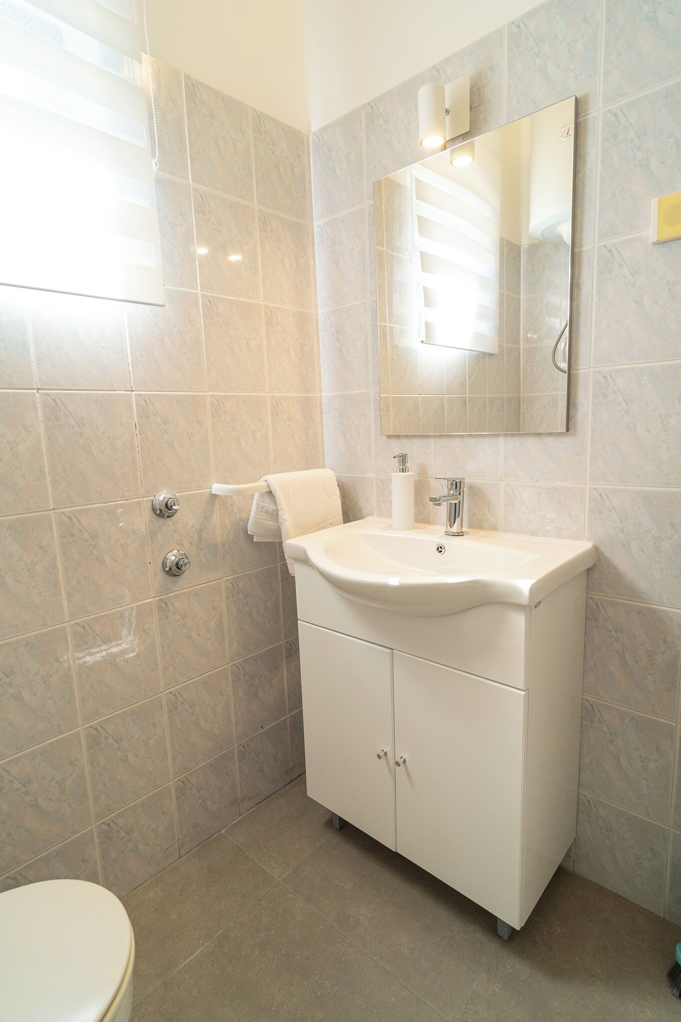 Un bagno con lavandino, specchio e WC bianchi.
