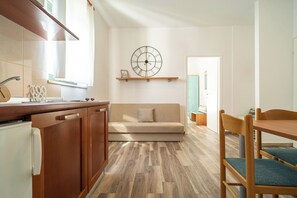 A modern kitchen with wooden cabinets, a built-in oven, and a dining area with a wooden table and chairs. - Zadar Leisure Suites (Zadar)