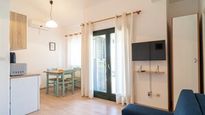 Een knus verblijf met kitchenette, een eethoek, een bank en een aan de wand bevestigde televisie.