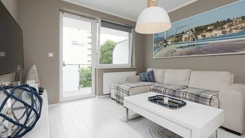 Una sala de estar moderna con un sofá, una mesa de centro, una lámpara colgante y un ventanal con vistas a un edificio.