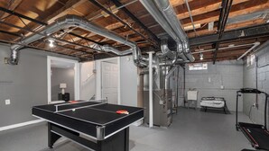 Una mesa de ping pong en una habitación con una cinta de correr y un banco para pesas.