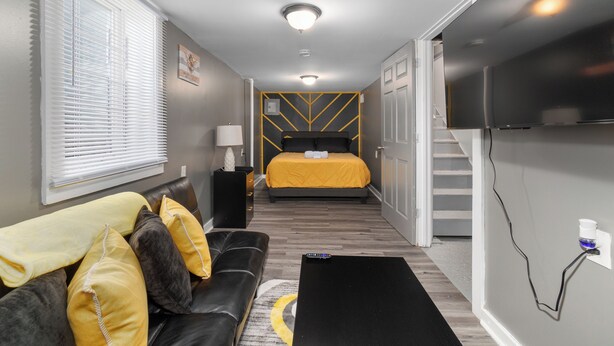 Una habitación de hotel moderna con cama, sofá, televisión y una escalera.
