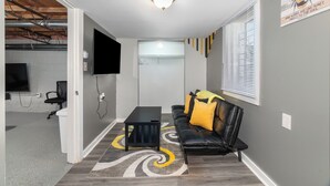 Una sala de estar moderna con un sofá de cuero negro, una mesa de centro negra y un tapete estampado.