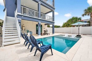 A two-story house with a swimming pool, outdoor seating, and a covered patio area.