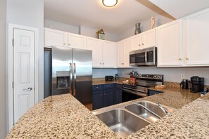 A modern kitchen with white cabinets, a stainless steel refrigerator, a microwave, and a coffee maker.
