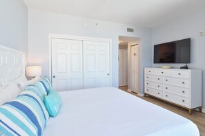 A bedroom with a bed, a dresser, a television, and a door.