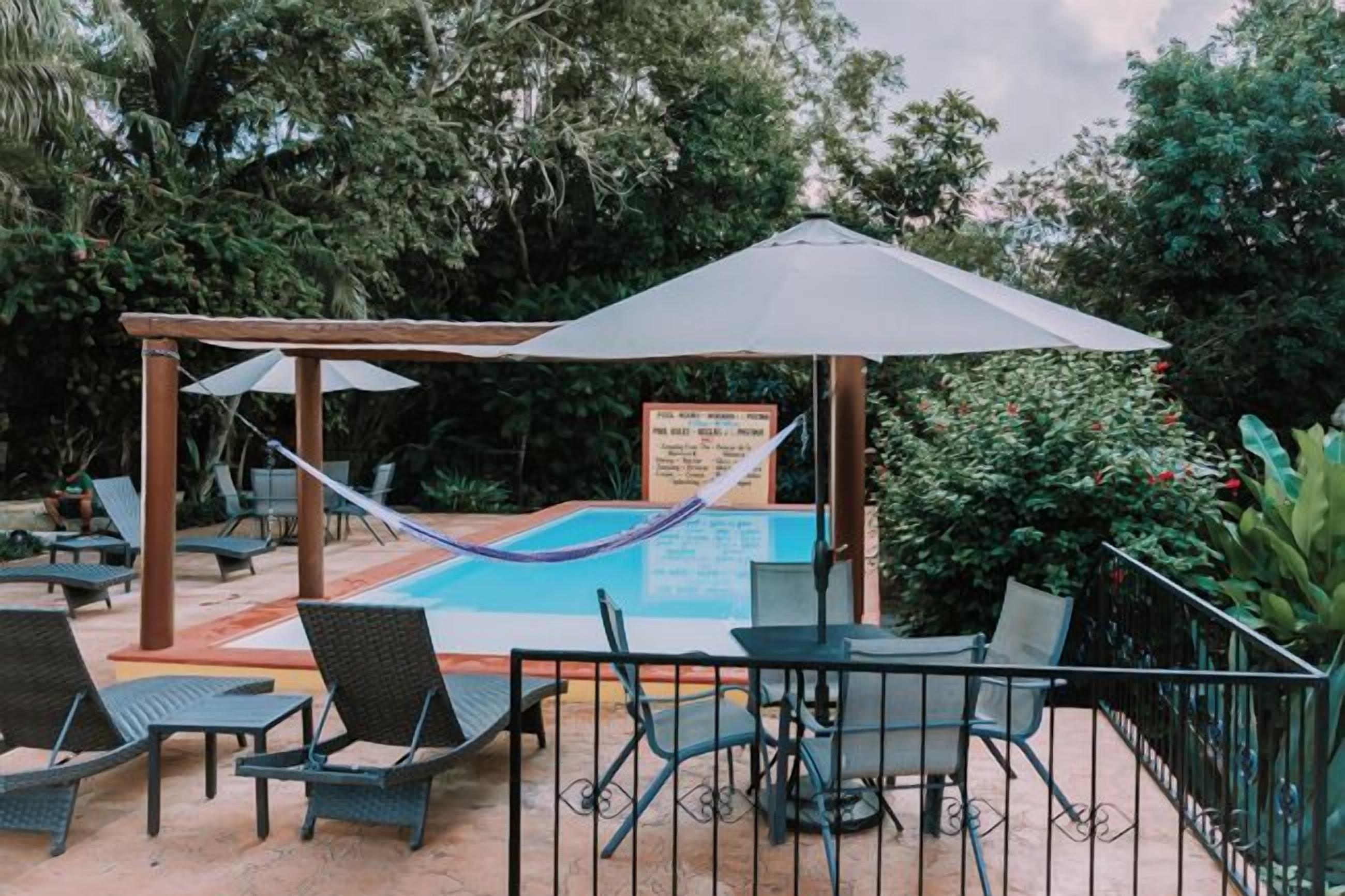 An outdoor pool area with lounge chairs, a hammock, and a covered seating area.