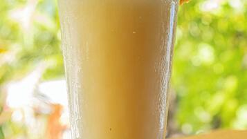 A tall glass with a frothy beverage, a cherry garnish, and a blurred green background.
