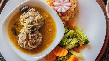 A plate with meatballs in a yellow sauce, rice, and vegetables.