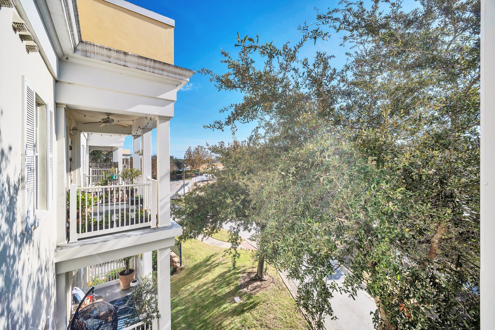 A residential building with a balcony, a tree, and a clear sky.