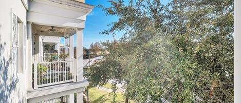 A residential building with a balcony, a tree, and a clear sky.