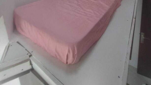 A small, single-bed room with a white bed and a pink bedspread. - Hassani (Dubai)
