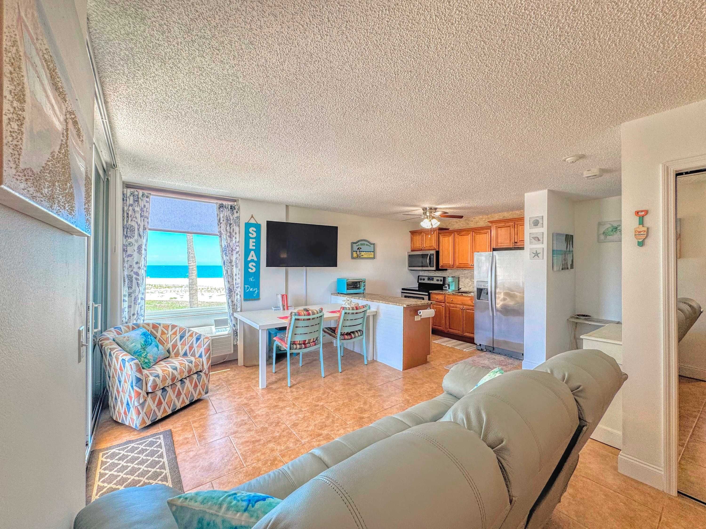 A compact living space with a kitchenette, a dining area with a table and chairs, a sofa, and a television.