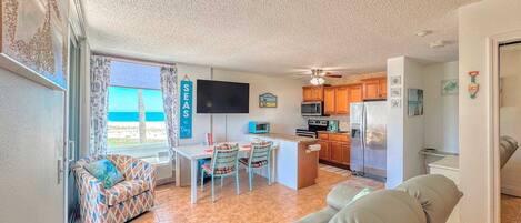 A compact living space with a kitchenette, a dining area with a table and chairs, a sofa, and a television.