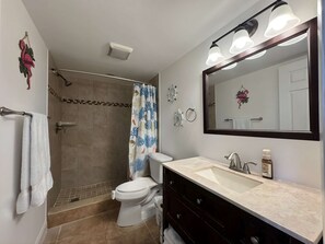 Une salle de bain équipée d’une douche, de toilettes, d’un lavabo et d’un grand miroir.
