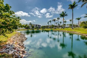 A calm lake with palm trees and a building in the background.