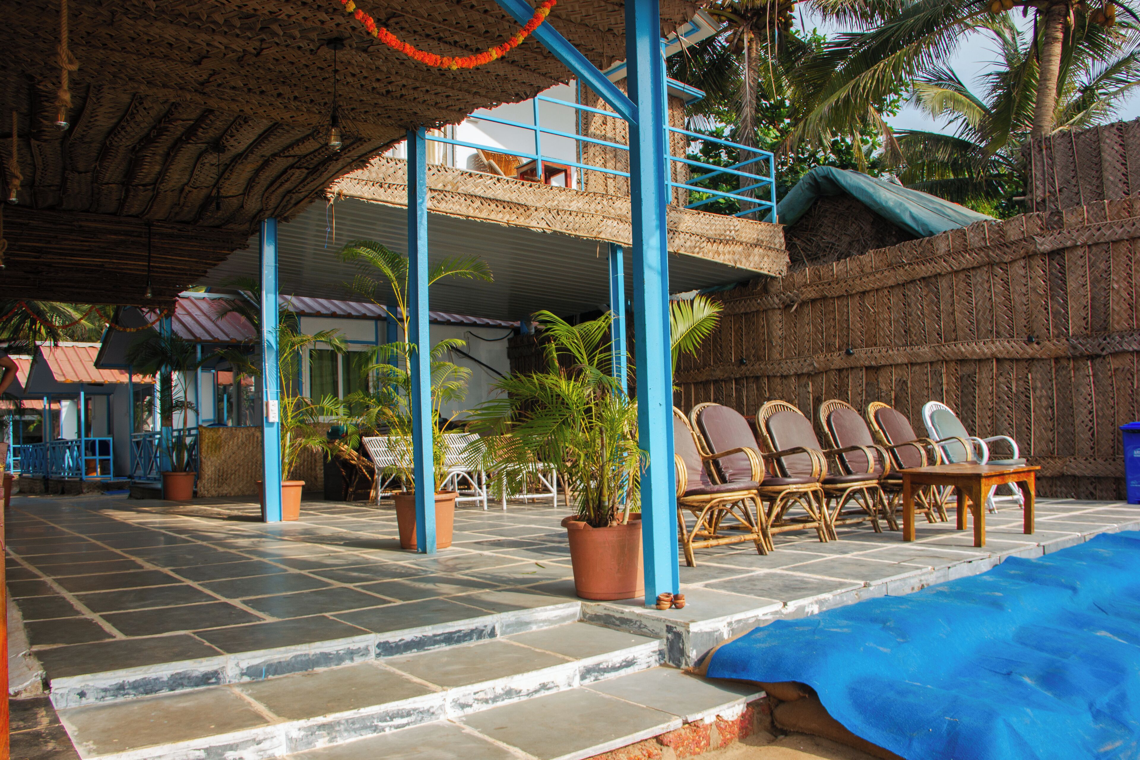 A covered outdoor seating area with chairs and potted plants.