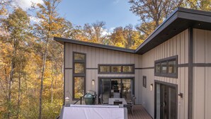 A modern cabin with a deck, large windows, and a view of autumn trees. - Altitude Adjustment by Innsbrook Vacations! (Innsbrook)