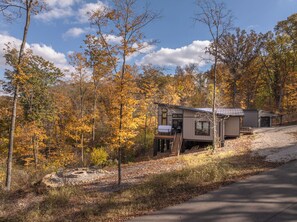 A cabin with a deck and a small porch, surrounded by autumn trees. - Altitude Adjustment by Innsbrook Vacations! (Innsbrook)